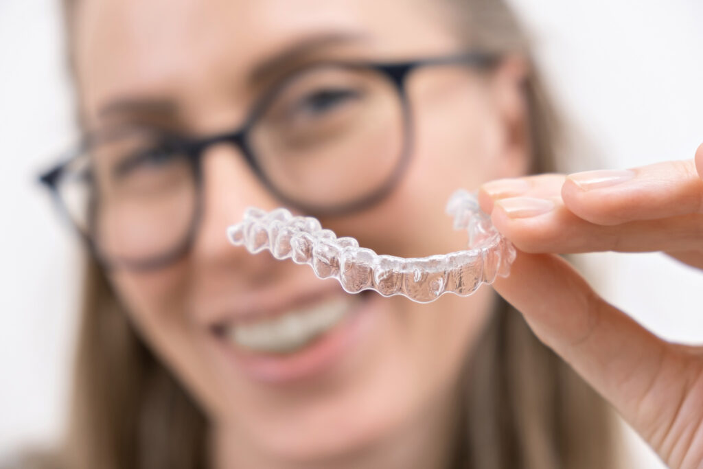 Donna sorridente che usa un apparecchio ortodontico rimovibili in plastica trasparente per riallineare i denti